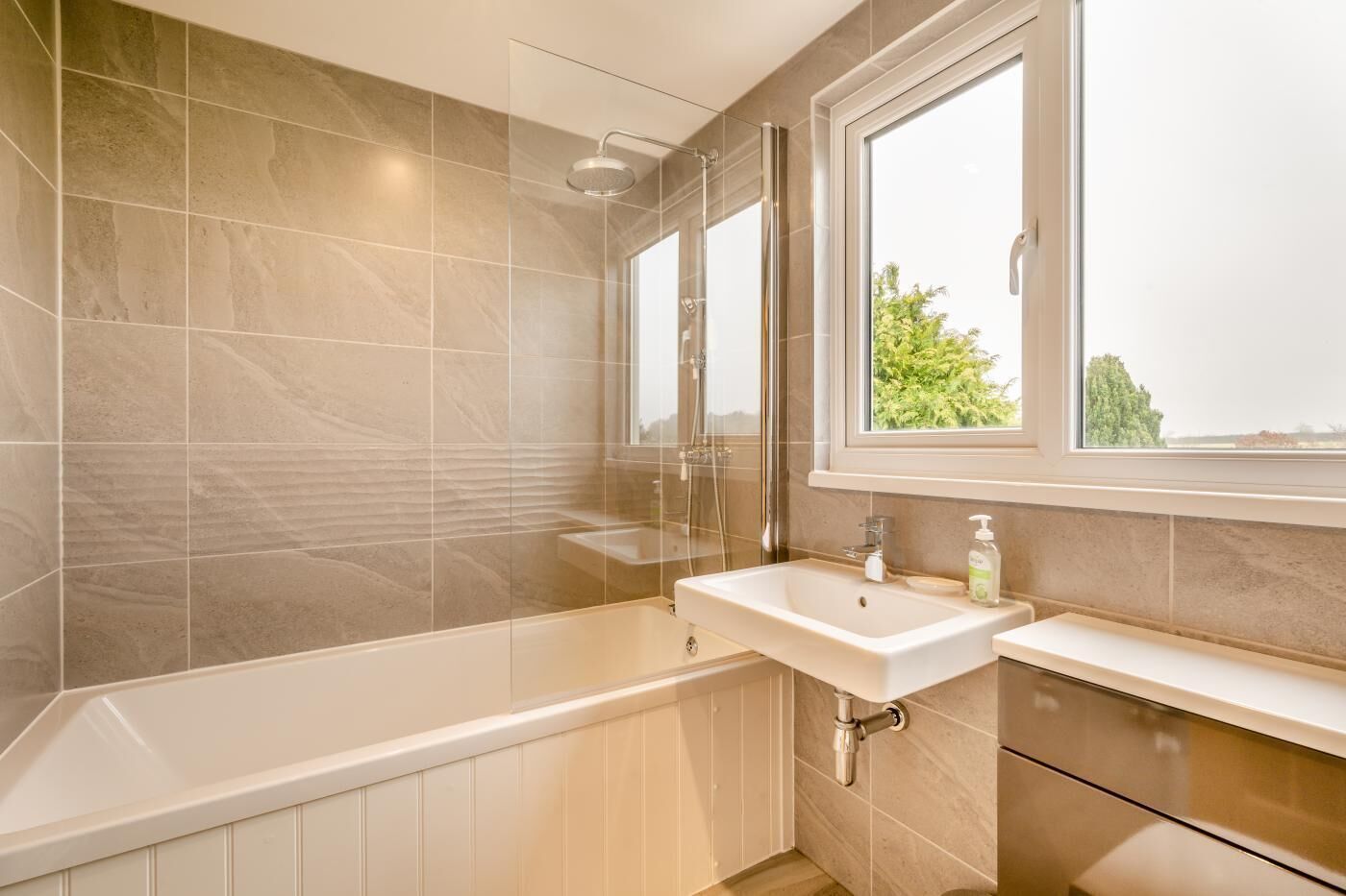 A bathroom with a bathtub, a sink, and a window.