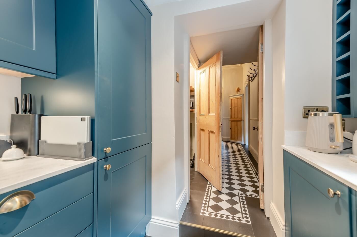 A kitchen with blue cabinets, a checkered floor, and a coffee maker on the counter.