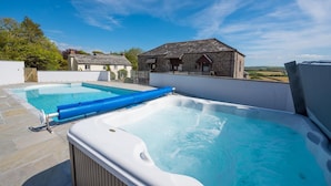 A rooftop pool area with a hot tub and a smaller pool, surrounded by stone buildings and a clear sky. - 4 Bed in Marhamchurch (oc-p34749) (Marhamchurch)