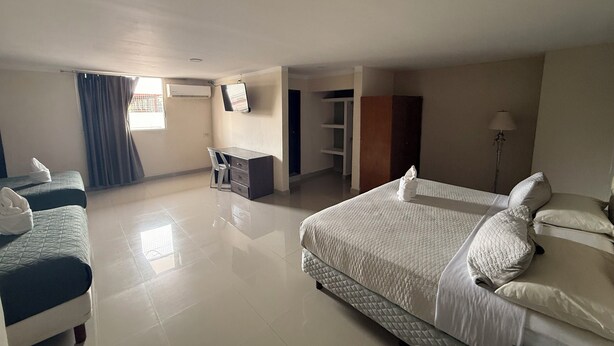 A hotel room with two beds, a desk, a chair, a wardrobe, and a TV. - EL BARON HOTEL (Tapachula)