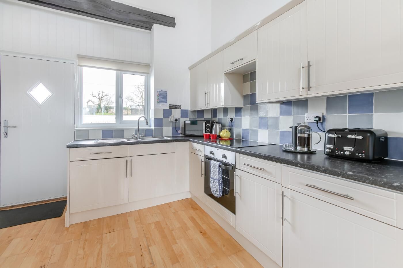 Een moderne keuken met witte kasten, een zwart aanrecht, een koffiezetapparaat en een broodrooster.