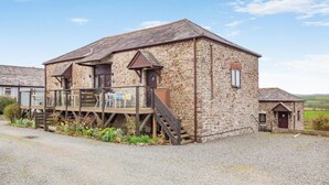 A stone building with a wooden deck and a staircase leading to a second floor. - 2 Bed in Marhamchurch (oc-s34752) (Marhamchurch)