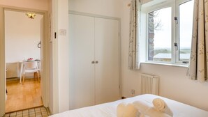 Une chambre à coucher avec un lit, une armoire, une fenêtre avec des rideaux et une vue sur l’extérieur.