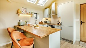 Una cocina moderna con una isla de madera, un microondas empotrado y una estufa a gas.