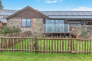 A stone building with a wooden roof, a glass conservatory, and a wooden fence. - 1 Bed in Thorncombe (oc-t34792) (Thorncombe)