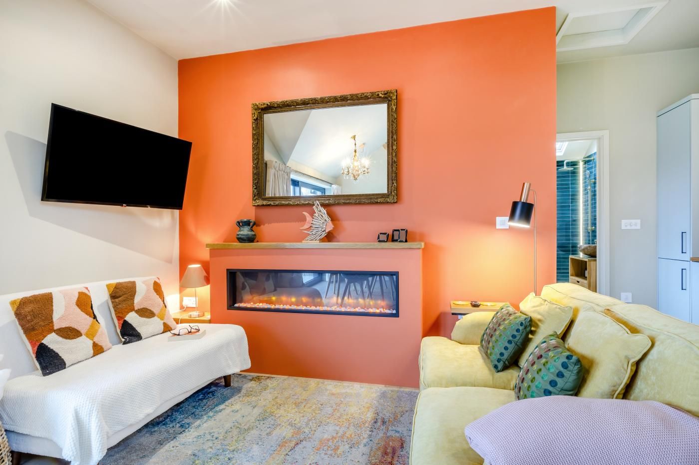 Een woonkamer met een open haard, een flatscreen televisie en een bank.