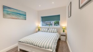 Quarto com uma cama, duas mesas de cabeceira, uma janela com vista e um quadro na parede.