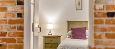 Un dormitorio con una cama, una mesita de noche, una lámpara y un cuadro en la pared.