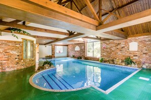 An indoor swimming pool with a brick wall and wooden beams. - 3 Bed in Stratton Strawless (oc-w34832) (Stratton Strawless)
