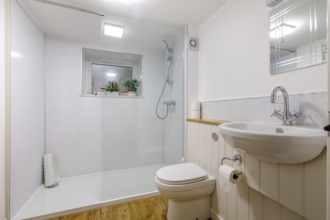 Ein Badezimmer mit einer Duschkabine, einer Toilette und einem Waschbecken mit Spiegel.