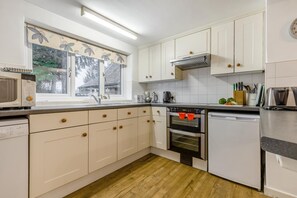 A modern kitchen with white cabinets, a microwave, an oven, and a dishwasher. - 3 Bed in Stratton Strawless (oc-w34832) (Stratton Strawless)