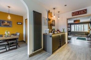 Une cuisine moderne avec un coin repas, un plancher en bois et un panneau décoratif sur le thème de la cuisine.