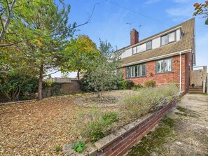 Il s’agit d’une propriété résidentielle comprenant une maison en briques, un jardin avec une grande variété de plantes et un ciel dégagé.