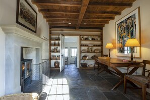 A hallway with a fireplace, open shelves with decorative items, a dining table with chairs, and a lamp. - 4 Bed in Middleham (oc-c34754) (Caldbergh)