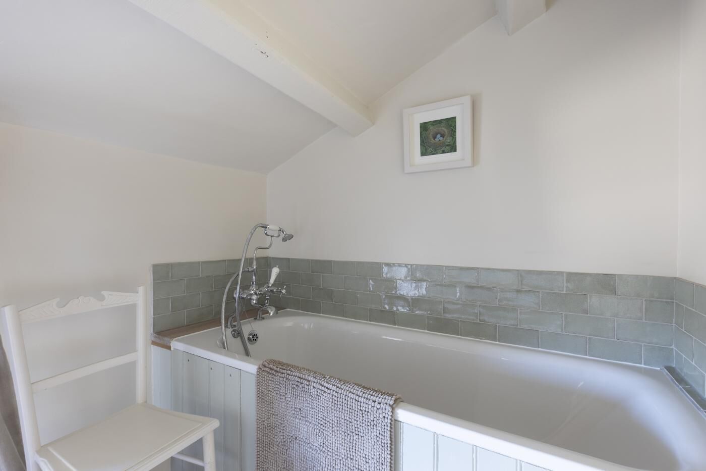 A bathroom with a bathtub, a towel rack, and a picture on the wall.
