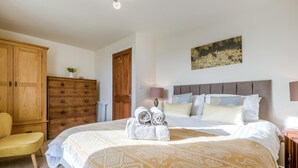 Ein Schlafzimmer mit einem Bett, einer Holzkommode, einem Stuhl und einem Bild an der Wand.
