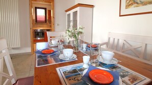 Una mesa de comedor dispuesta con platos, tazas y un florero.