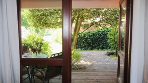 Un patio in legno che conduce a un giardino con tavolo e sedie.