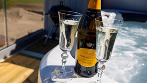 Poreallas, jonka vieressä on puinen terassi ja sen päällä kaksi lasia Prosecco-kuohuviiniä.