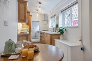 A modern kitchen with wooden cabinets, a dining table with breakfast items, and a window with a view. - 2 Bed in Hunningham (oc-h34740) (Hunningham)
