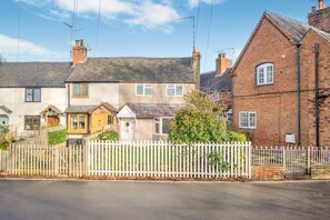 A row of terraced houses with a white picket fence, a paved driveway, and a clear sky. - 2 Bed in Hunningham (oc-h34740) (Hunningham)