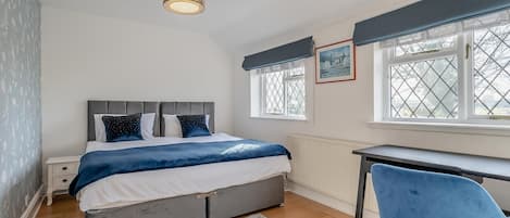 Een slaapkamer met een bed, nachtkastje, stoel en een raam met uitzicht.