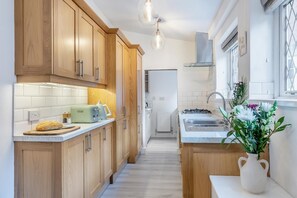 A modern kitchen with wooden cabinets, a countertop with a bread loaf, a toaster, and a vase with flowers. - 2 Bed in Hunningham (oc-h34740) (Hunningham)