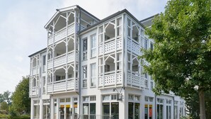 Een wit gebouw met meerdere balkons en etalages, waarschijnlijk een hotel of commercieel complex.