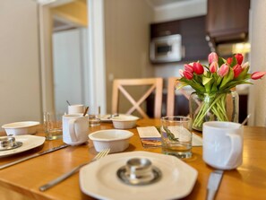 A dining table set with plates, bowls, glasses, and a vase with tulips. - Stilvoll Eingerichtete Ferienwohnung mit Grossem Balkon in Sellin (Sellin)