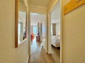 A hotel corridor with a bed, a TV, and a chair in the room. - Stilvoll Eingerichtete Ferienwohnung mit Grossem Balkon in Sellin (Sellin)