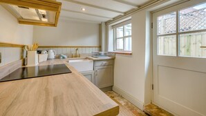 A kitchen with a wooden countertop, a window with a lattice design, and a door with a white frame. - 1 Bed in Holt (oc-p34797) (Holt)