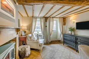 A cozy room with exposed wooden beams, a white sofa, a TV, and a fireplace. - 1 Bed in Holt (oc-p34797) (Holt)