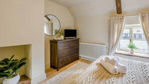 A bedroom with a bed, a dresser, a mirror, a radiator, a window with curtains, and a plant. - 1 Bed in Holt (oc-p34797) (Holt)
