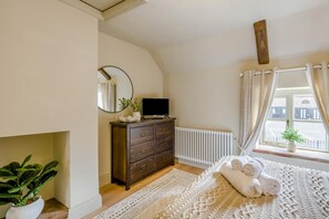 A bedroom with a bed, a dresser, a mirror, a radiator, a window with curtains, and a plant. - 1 Bed in Holt (oc-p34797) (Holt)