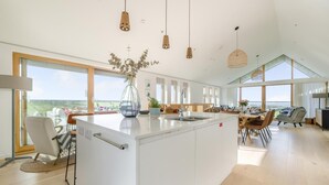 A spacious kitchen with a large island, modern pendant lights, and large windows offering a view. - 3 Bed in St. Eval (oc-s32502) (Saint Eval)