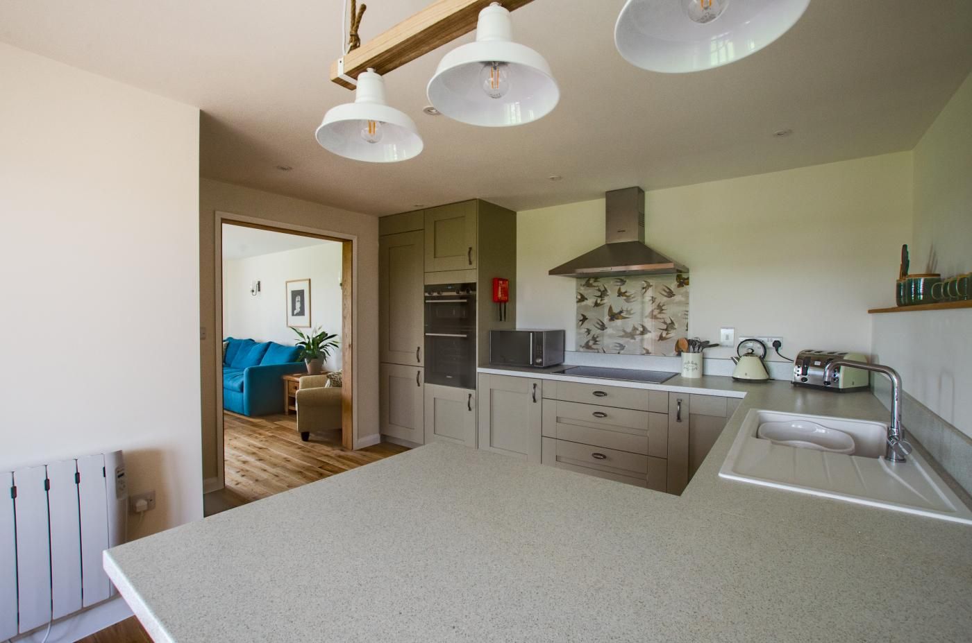 A modern kitchen with a large island, stainless steel appliances, and pendant lighting.