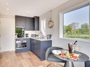 Eine moderne Küche mit grauen Schränken, einem eingebauten Ofen und einem Fenster mit Blick auf eine grüne Landschaft.