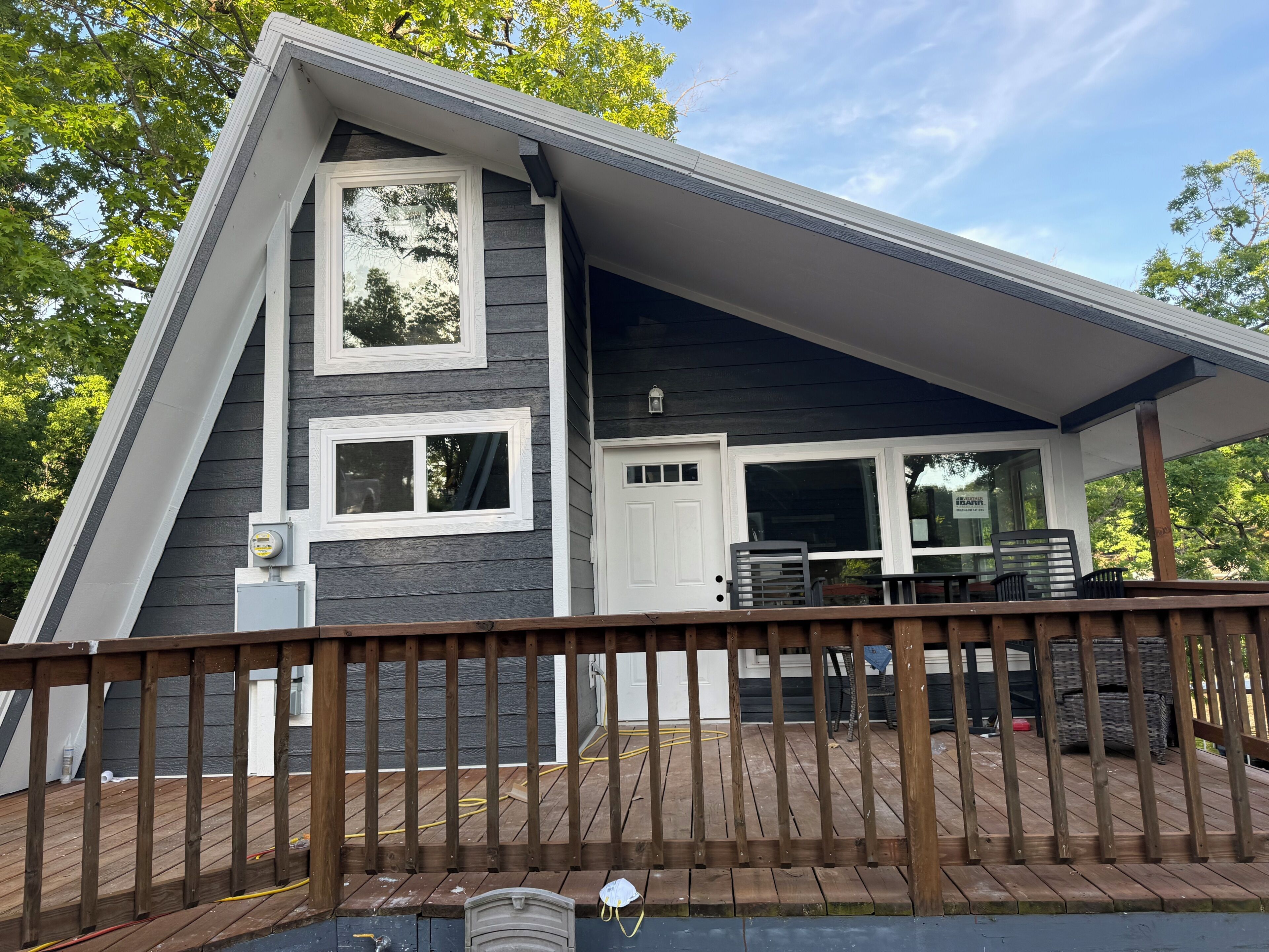 Une maison moderne dotée d’une terrasse, d’une porte de garage et d’une fenêtre donnant sur la forêt.