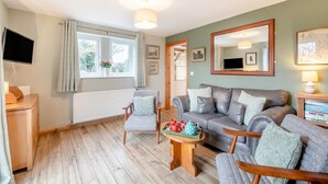 Ein gemütliches Wohnzimmer mit einer Couch, Sesseln, einem Couchtisch und einem Fernseher.