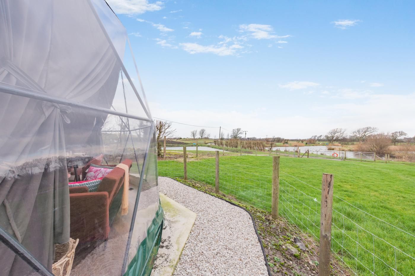 A tent with a view of a grassy field and a body of water.