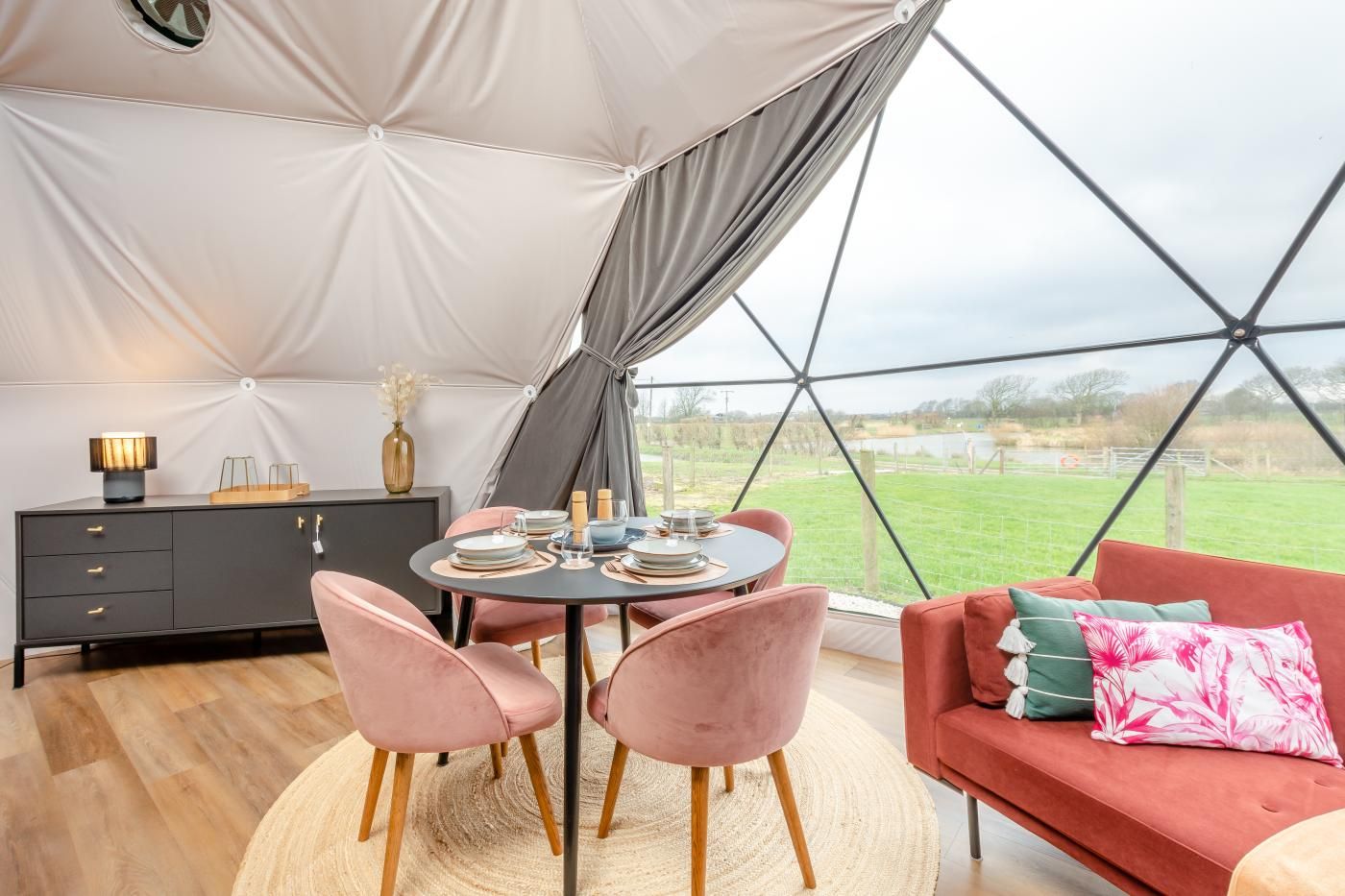 A tented accommodation with a dining table, chairs, a sofa, and a cabinet.