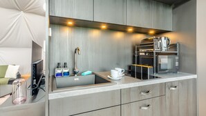 Et moderne køkken med indbygget kaffemaskine, mikroovn og vask.