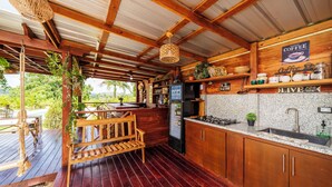 A rustic kitchen with wooden cabinets, a refrigerator, a coffee sign, and a wooden bench. - Villa Campestre by Otium (Higüey)