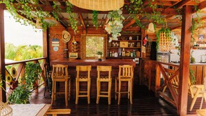 A wooden bar area with three wooden chairs, a wooden counter, and various bar items. - Villa Campestre by Otium (Higüey)