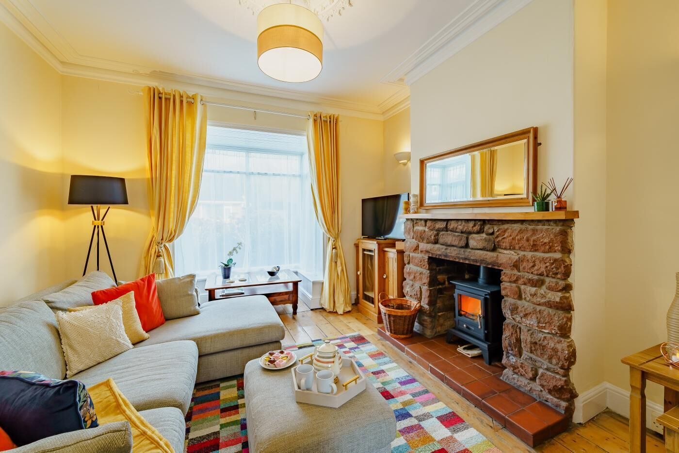 A cozy living room with a sofa, a coffee table, a fireplace, and a television.