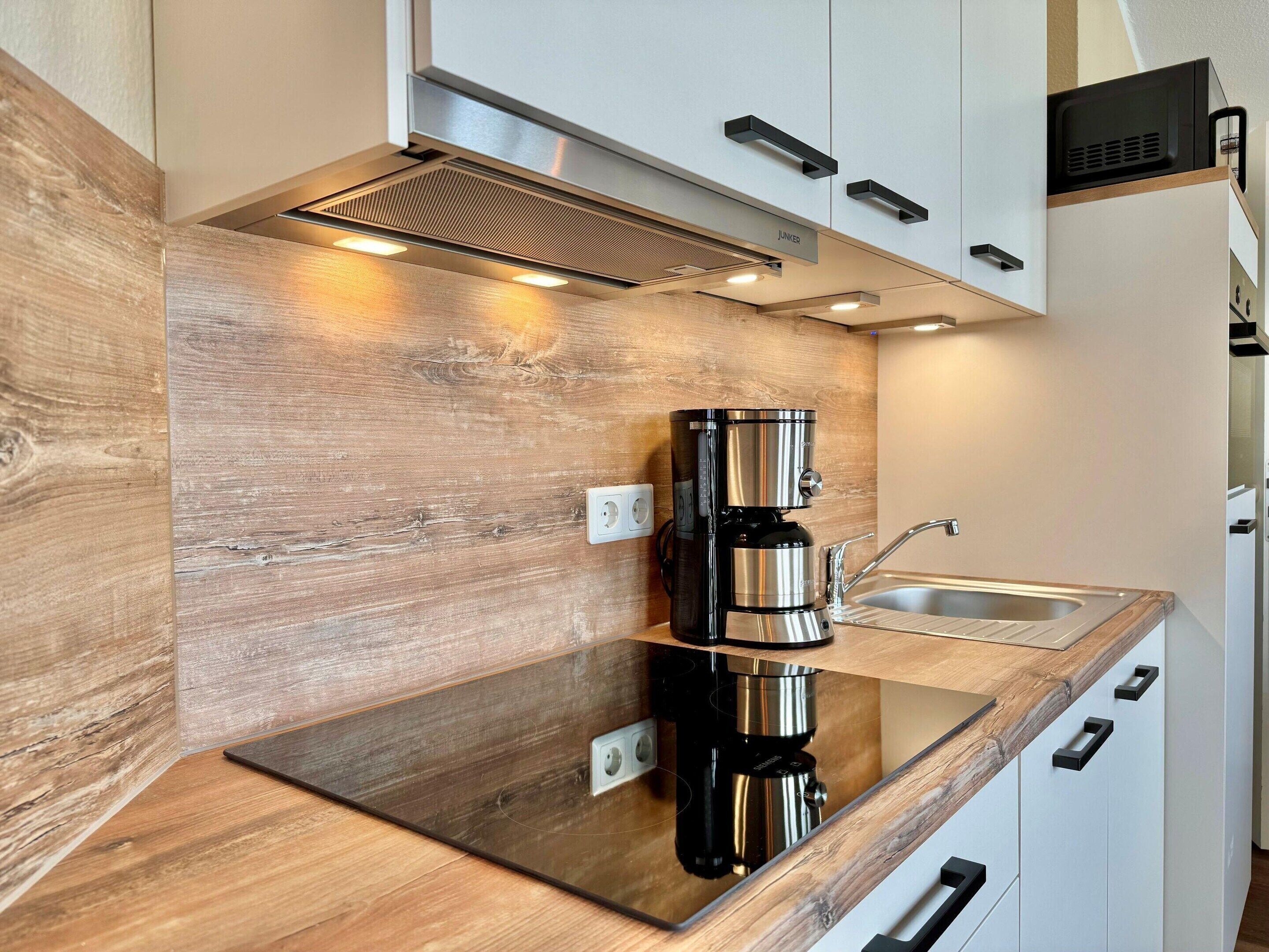 A modern kitchen with a stainless steel coffee maker, a sink, and wooden cabinetry.