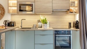 A modern kitchen with a built-in microwave, coffee maker, and oven. - 1 Bed in Exmouth (oc-c33052) (Exmouth)