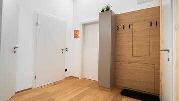 Un couloir doté d’un plancher en bois, de murs blancs et d’une porte en bois avec une poignée noire.