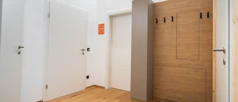 A hallway with wooden flooring, white walls, and a wooden door with a black handle.