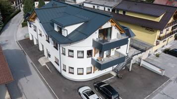 Un immeuble à plusieurs étages doté d’une façade incurvée, d’un balcon et d’un espace de stationnement pouvant accueillir deux voitures.